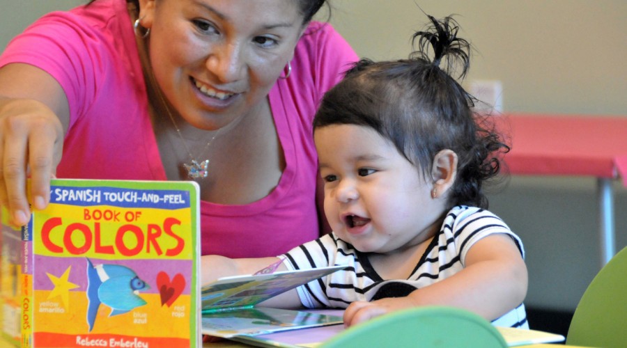 Toddler and mom reading book called Spanish Touch and Feel, Book of Colors by Rebecca Emberly