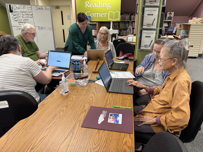 Adult students and staff working on computers in the Literacy Center