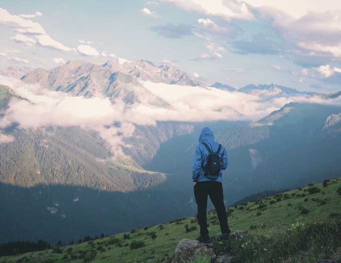 Man with backpack staring at a mountain range