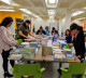 Six literacy staff members sort a children's book delivery around a large table.