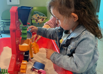 Toddler girl playing with sand at playgroup.